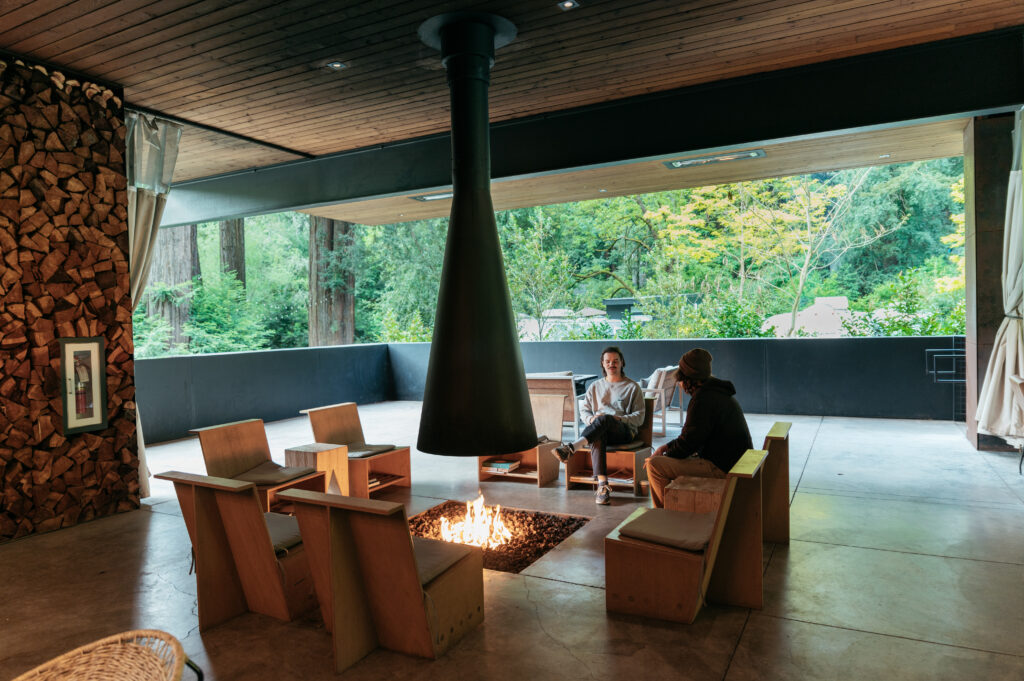 two people sitting by the fire pit inside the clubhouse at AutoCamp Sonoma